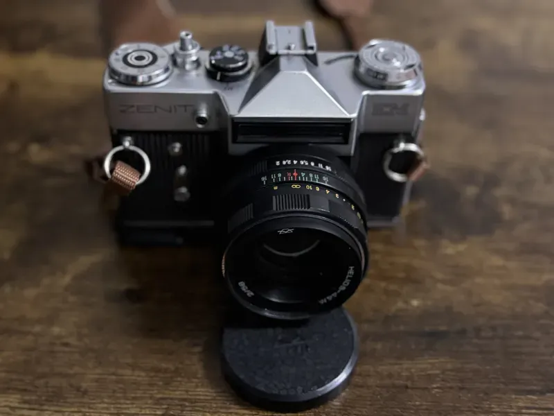 Zenit EM film camera with lens and cap resting on a wooden table.